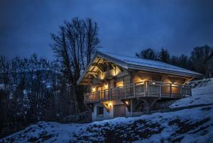 una gran casa de madera con luces en la nieve en Chalet du Piedmont, en Cornimont