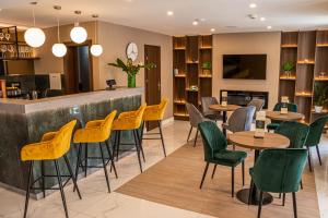 豪伊杜索博斯洛的住宿－Hotel Crystal，一间设有黄色桌椅的餐厅和一间酒吧