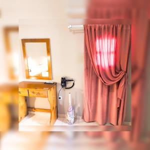 - un rideau rouge à côté d'un bureau avec un miroir dans l'établissement Le stanze del tramonto di Eleni, à Lipsi