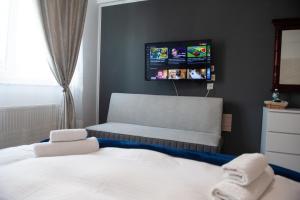 1 dormitorio con 1 cama y TV en la pared en SIA Residence, en Otopeni