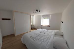 - une chambre blanche avec un lit et une fenêtre dans l'établissement La Cigogne, moderne, spacieux et bien placé, à Thury-Harcourt