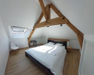 - une chambre avec un grand lit blanc et du parquet dans l'établissement La Cigogne, moderne, spacieux et bien placé, à Thury-Harcourt