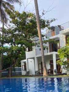 une villa avec une piscine en face d'une maison dans l'établissement The Pearl, à Marawila