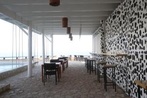 uma sala de jantar com mesas e cadeiras e uma parede de janelas em Begona Cliff Hotel em Negril