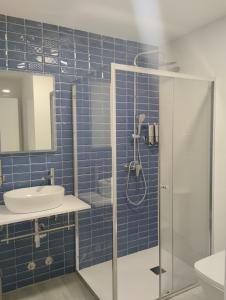 uma casa de banho em azulejos azuis com um chuveiro e um lavatório. em Finca El Rabil em Cangas de Onís