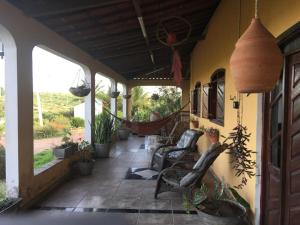 eine Veranda eines Hauses mit Stühlen und einer Hängematte in der Unterkunft Recanto do Ipês in Garanhuns