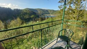 a chair on a balcony with a view of a river and mountains at Chata Julka in Dedinky