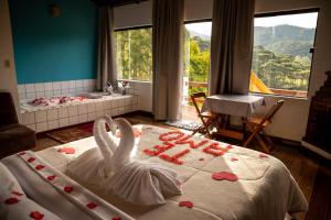 Un dormitorio con dos cisnes hechos de corazones sobre una cama. en Pousada Som das Aguas, en Gonçalves