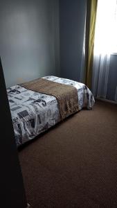 Una cama en un dormitorio con colcha. en Hostal tepual puerto montt en Puerto Montt