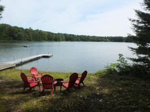un grupo de sillas y una mesa junto a un lago en Cub Hill Chalet - Private Lakefront With Spa!, en Kalkaska