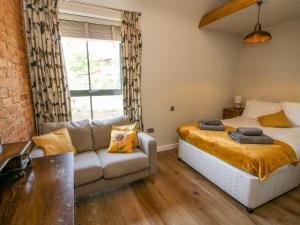 a bedroom with a bed and a couch and a window at The Mission Room in Malpas