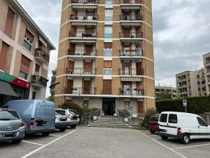 a tall building with cars parked in a parking lot at Rosanna House - Vedano Al Lambro in Monza