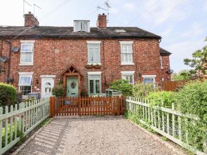 an old brick house with a wooden fence at Wisteria Cottage in Nantwich