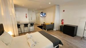 a bedroom with a bed and a kitchen with a television at Original Studio Downtown in Albufeira