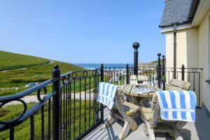 a table and chairs on a balcony with a view of the ocean at Beachcombers Apartments in Newquay