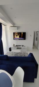 a bedroom with a blue couch and a tv on the wall at Euphoria Neptun Oxygen in Neptun