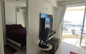 a room with a television and a bed and a balcony at Apto vista p/ mar 7º andar in Fortaleza
