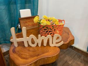 a wooden sign that says home on a table with flowers at Tu Cabaña en Boquete in Alto Boquete