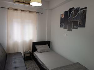 sypialnia z łóżkiem, kanapą i oknem w obiekcie Renas home w mieście Anavissos