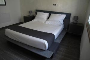 um quarto com uma cama grande com lençóis brancos e almofadas em Dimora Due Galli em Ponti Sul Mincio