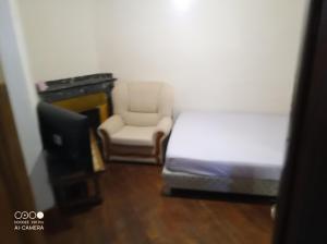 een slaapkamer met een bed, een stoel en een televisie bij Chambre à petit budget pour personne simple in Saint-Laurent-de-Neste