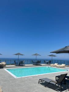 a swimming pool with chairs and umbrellas next to the ocean at MELIKIRON LUXURY APARTMENTS in Agios Nikitas