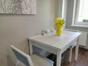 a white table with a yellow vase of flowers on it at Micromegas apartments in Chernivtsi