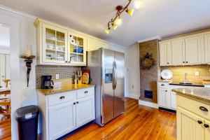 La cuisine est équipée de placards blancs et d'un réfrigérateur en acier inoxydable. dans l'établissement Tannery Brook Cottage, à Bucksport