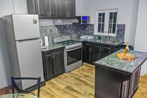 a kitchen with black cabinets and a white refrigerator at Villa De Cruz - Deluxe Suite in Scarborough