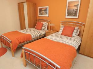 two beds in a room with orange walls at Orchard Lodge in Warkworth