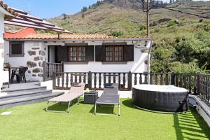 um quintal com uma banheira de hidromassagem e cadeiras e uma casa em Casa Abuelo Paco em Vega de San Mateo