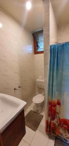 a bathroom with a toilet and a shower curtain at Lynn's Getaway Apartments in Apia
