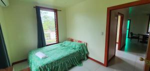 a bedroom with a bed with a green comforter and a window at Lynn's Getaway Apartments in Apia