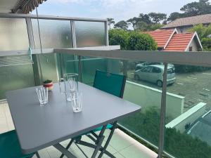 two glasses on a white table on a balcony at Appt calme au centre du Moulleau in Arcachon