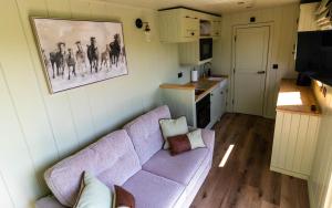 uma sala de estar com um sofá roxo e uma cozinha em The Shire Luxury Converted Horse Lorry with private hot tub Cyfie Farm em Llanfyllin