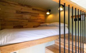 a bed in a room with a wooden wall at The Shire Luxury Converted Horse Lorry with private hot tub Cyfie Farm in Llanfyllin