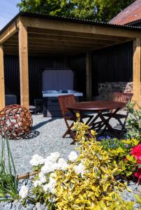 un patio con una mesa, un banco y flores en The Shire Luxury Converted Horse Lorry with private hot tub Cyfie Farm en Llanfyllin