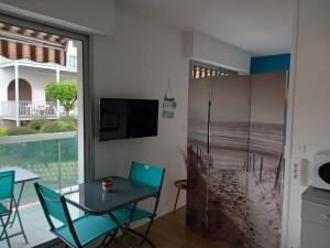 a dining room with a table and chairs and a television at Appt calme au centre du Moulleau in Arcachon