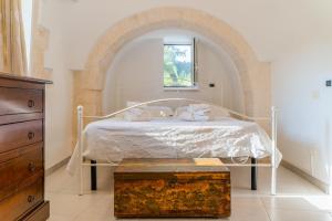 ロコロトンドにあるTrulli Francesca Cicloviaのベッドルーム1室(白いベッド1台、アーチ型のベッド付)
