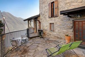 un patio con sedie e un tavolo e un edificio di Stone house and dependance 7 pers a Moltrasio