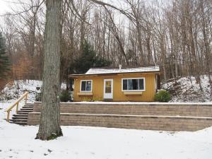 a small yellow tiny house in the snow at The Crystalaire Cabin - Charming And Relaxing! in Frankfort