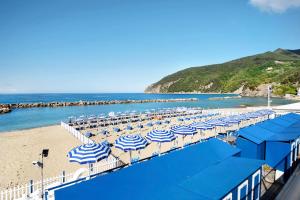 un tas de parasols bleus et blancs sur une plage dans l'établissement Appartamento Monolocale Moneglia 24, à Moneglia