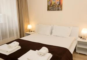 een slaapkamer met een groot wit bed en 2 handdoeken bij Coastal 1BD Flat with Pool & Parking in Varna
