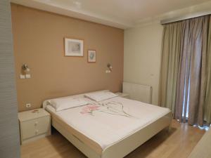 a bedroom with a bed with white sheets and flowers on it at Omeros in Gevgelija