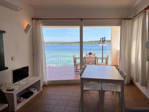 a living room with a table and a view of the ocean at ERMITA by SOM Menorca in Fornells