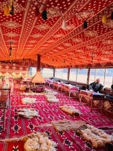 a large room with a red ceiling with tables and chairs at Bedouin friend camp in Wadi Rum