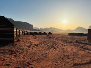 a desert with a fence and the sun in the distance at Bedouin friend camp in Wadi Rum