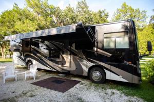 a black and white rv parked with two white chairs at River Safaris New Class A Motorcoach Homosassa with River Accessibility in Homosassa