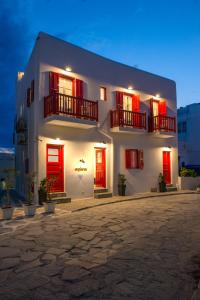 un edificio blanco con puertas y ventanas rojas por la noche en Orpheas Rooms, en Mykonos ciudad