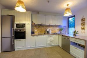 a kitchen with white cabinets and stainless steel appliances at Pensiunea Edelweiss, Putna in Putna